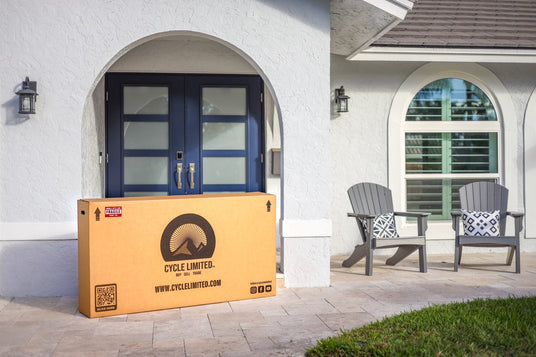 packaged box with cycle limited branding containing a bicycle, placed outside a doorstep