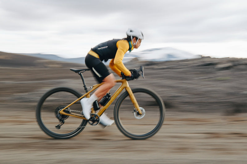cyclist riding a yellow road bike on a mountain path
